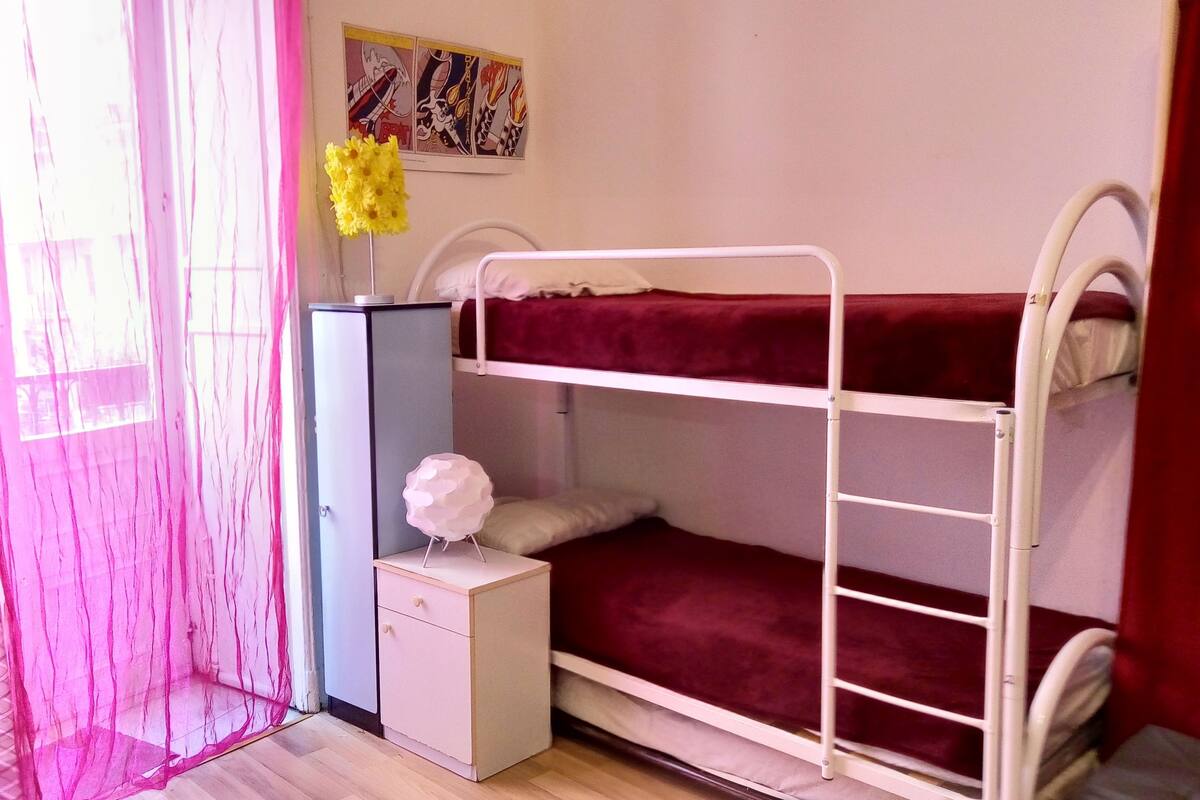 A bunk bed room with a desk and a small cabinet.