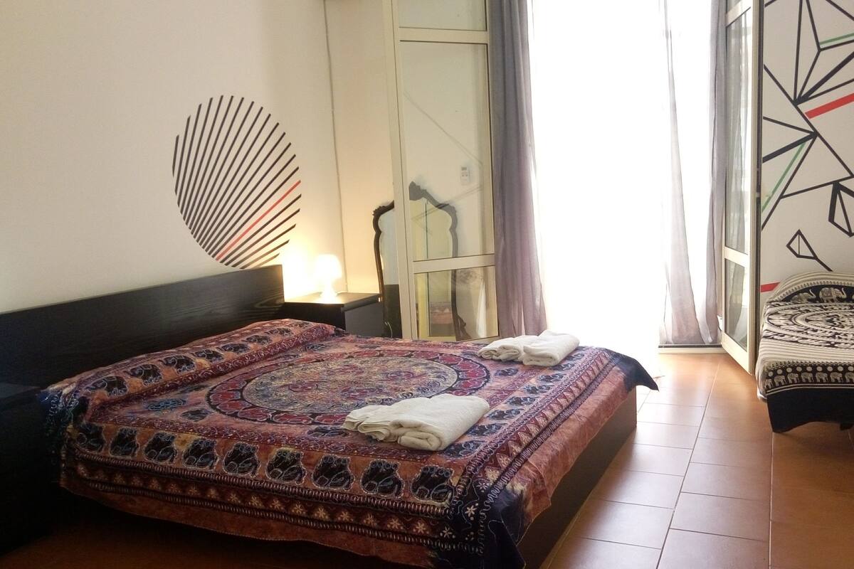A bedroom with a large bed, a nightstand, a dresser, and a chair.