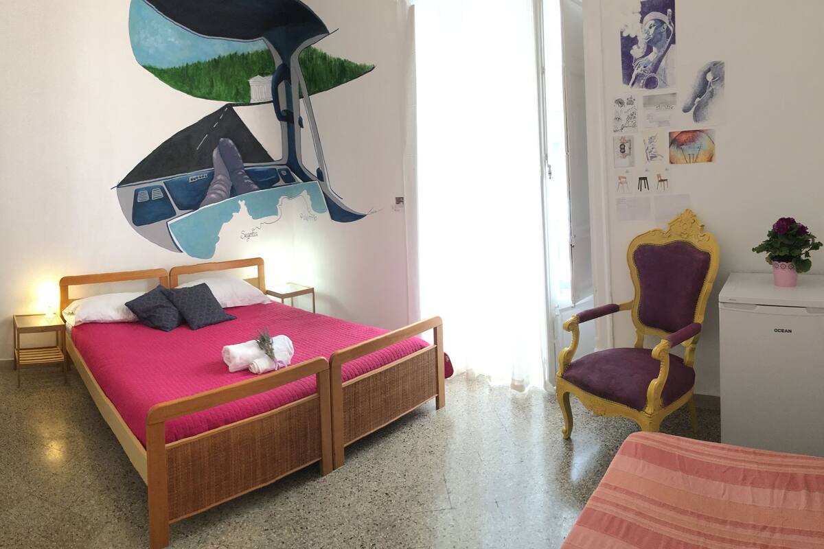 A bedroom with a wooden bed, a desk, a chair, and a mirror.