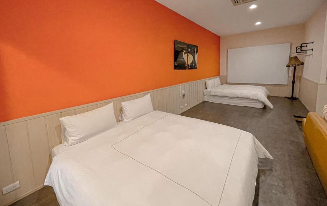 A hotel room with two beds, a large window, and a painting on the wall.