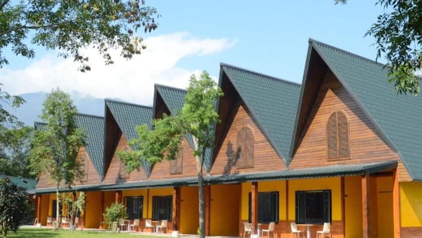 A row of cabins with sloped roofs and wooden exteriors, each with a window and a door, set in a grassy area with trees. - Ruixiong Hotspring Villa (Ruisui)