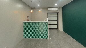 A reception area with a green patterned counter, a white air conditioning unit, and a grey wall with a green accent. - Ruixiong Hotspring Villa (Ruisui)