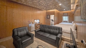 A compact room with a wooden ceiling, a bed, a sofa, a desk, and a television. - Ruixiong Hotspring Villa (Ruisui)