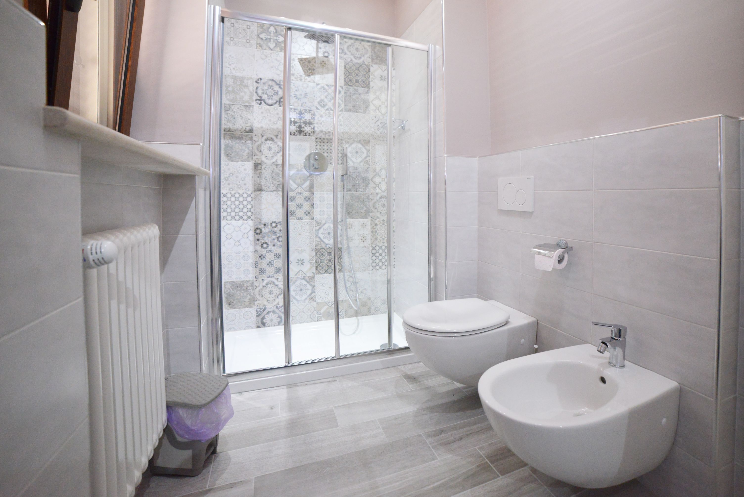 A bathroom with a shower, toilet, bidet, and tiled walls.