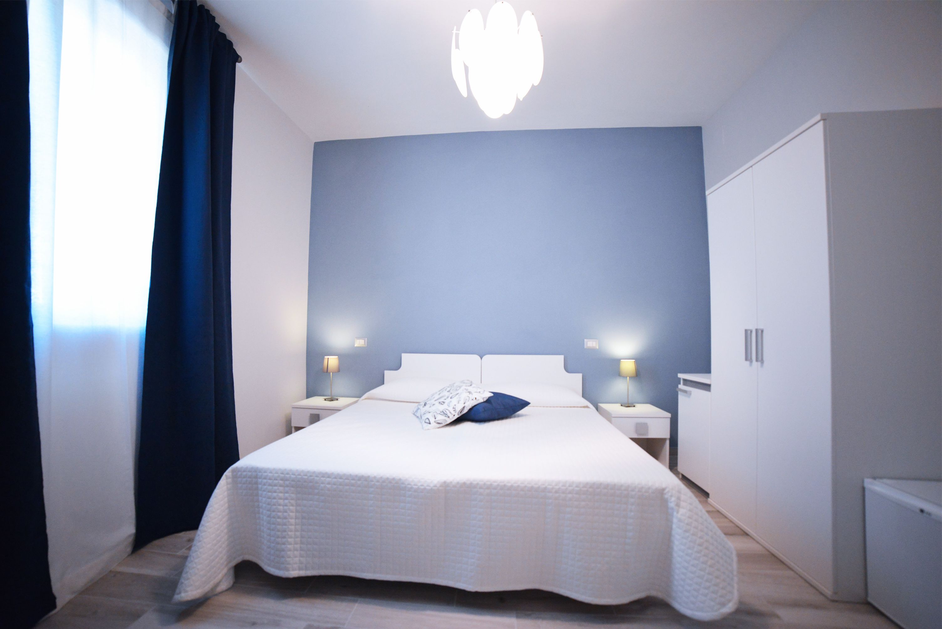 Un dormitorio ordenado con una cama grande, lámparas de noche, un armario y una lámpara en el techo.