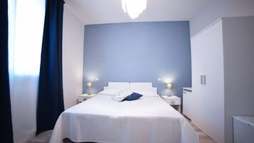Un dormitorio ordenado con una cama grande, lámparas de noche, un armario y una lámpara en el techo.