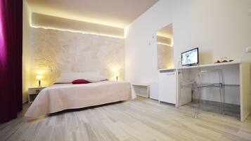 A modern bedroom with a bed, bedside lamps, a desk with a computer, and a chair.