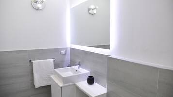 A modern bathroom with a white sink, a black vase, and a towel hanging on the wall.