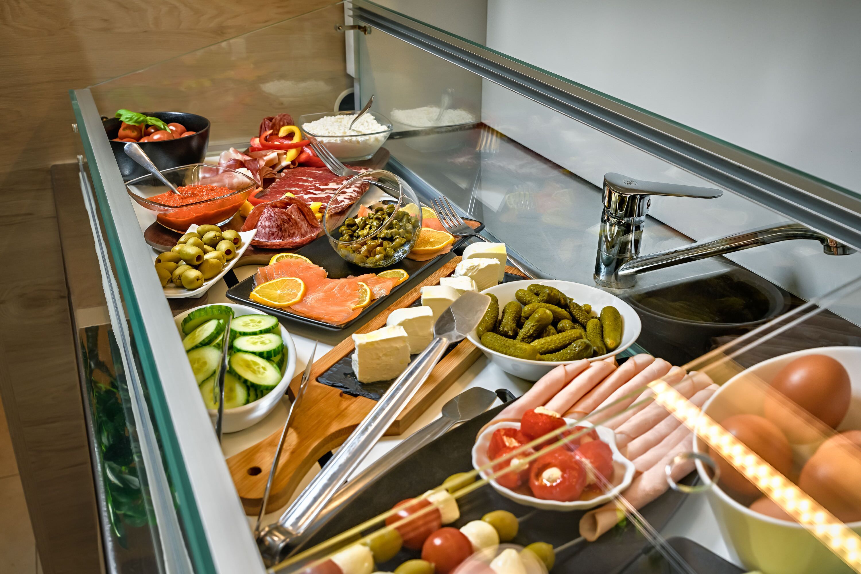 Un bufé con una variedad de alimentos, incluyendo carnes, quesos, frutas y verduras.