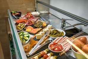 A buffet with various food items including meats, cheeses, fruits, and vegetables.
