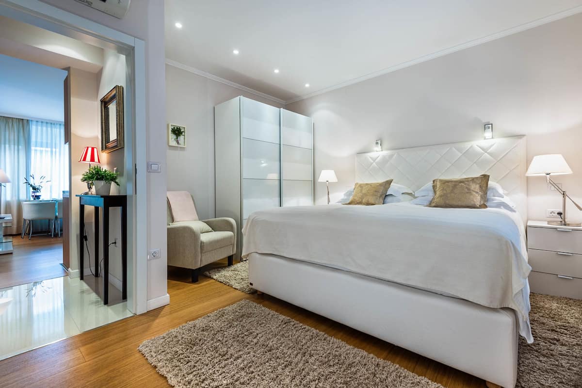 Un dormitorio moderno con una cama grande, un armario, un escritorio y una silla.