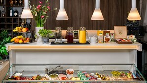 A buffet setup with various food items, a fruit display, and decorative elements like flowers and bottles. - Boutique Hotel Madison (Zagreb)