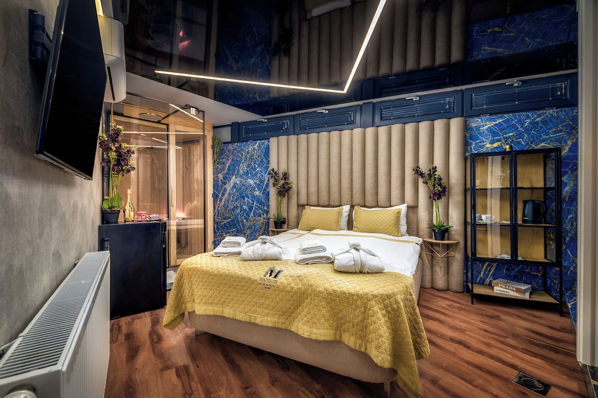 Una habitación de hotel moderna con una cama grande, un televisor de pantalla plana, un minibar y una pared con diseño de mármol.