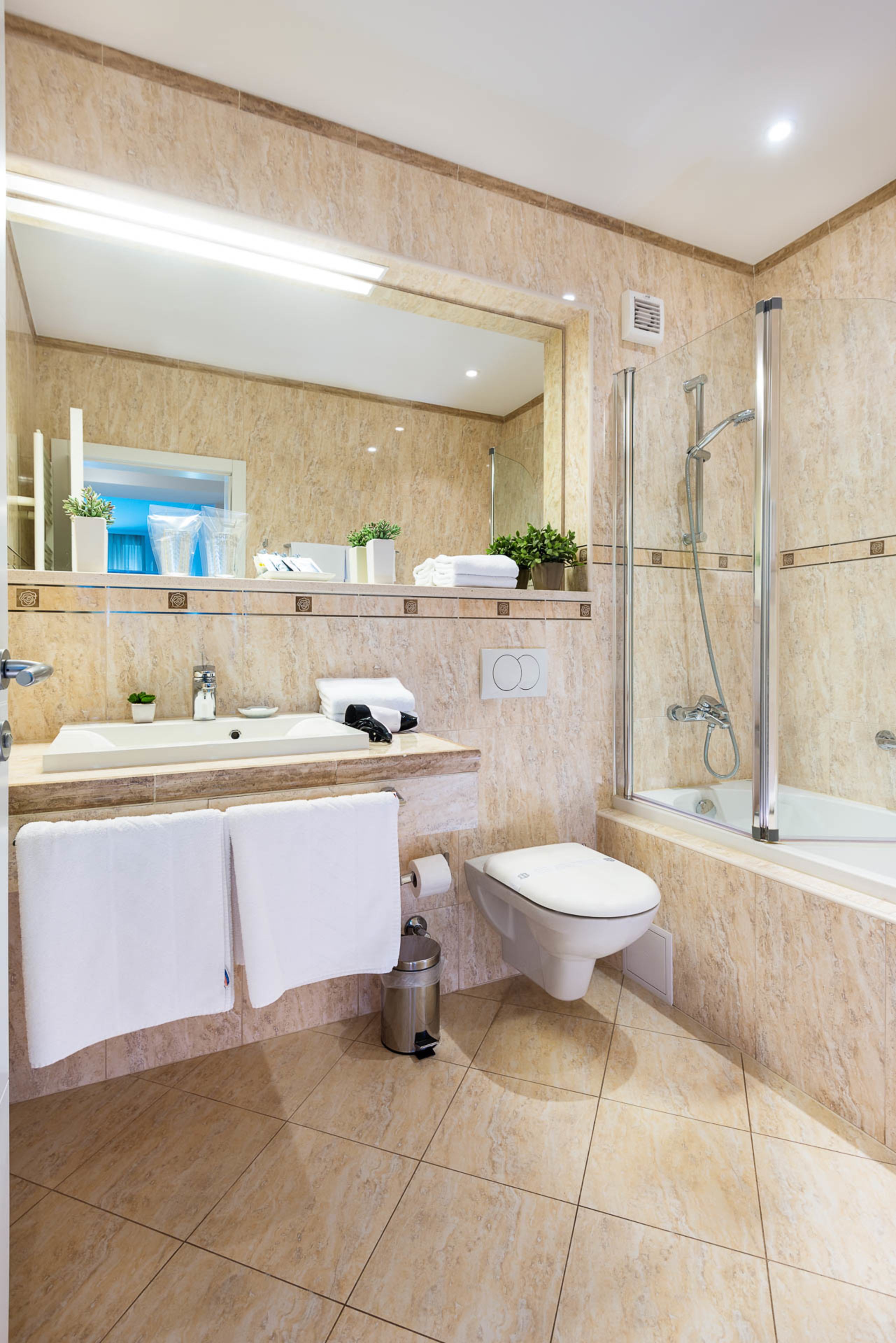 Une salle de bain moderne avec un grand miroir, un lavabo, des toilettes et une douche.