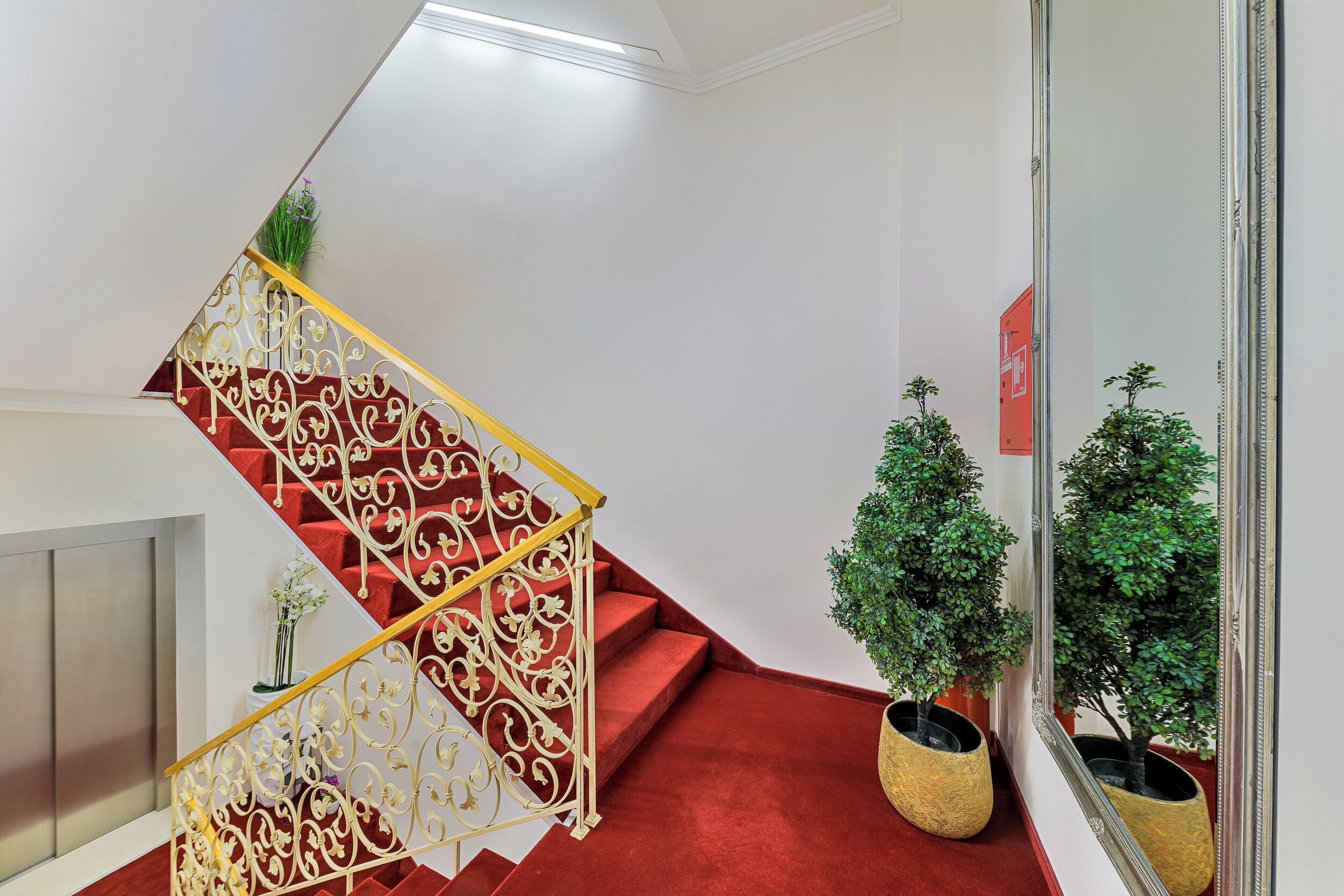A staircase with ornate golden railings and red carpeted steps.