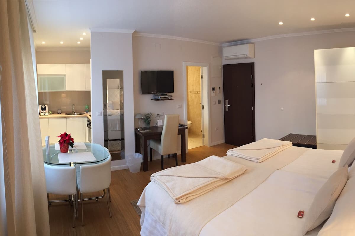 Una habitación de hotel con cama, escritorio, silla, televisor y baño.