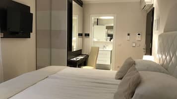 A modern hotel room with a large bed, a bedside table, a mirror, a wardrobe, and a TV mounted on the wall.