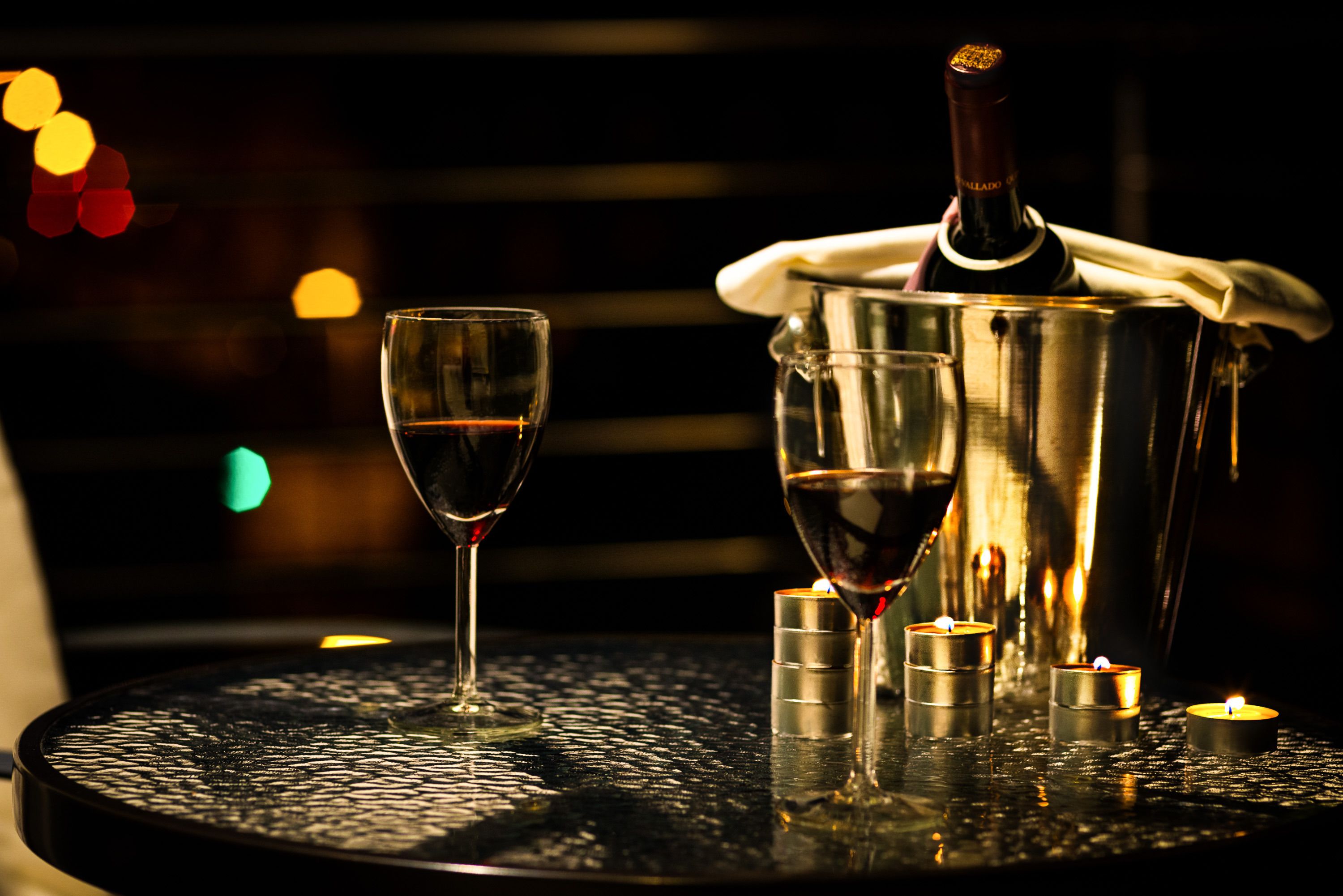 A table with a bottle of wine, two glasses, and candles.