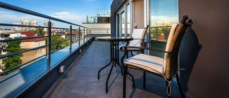 A balcony with a table and chairs, offering a view of the cityscape.