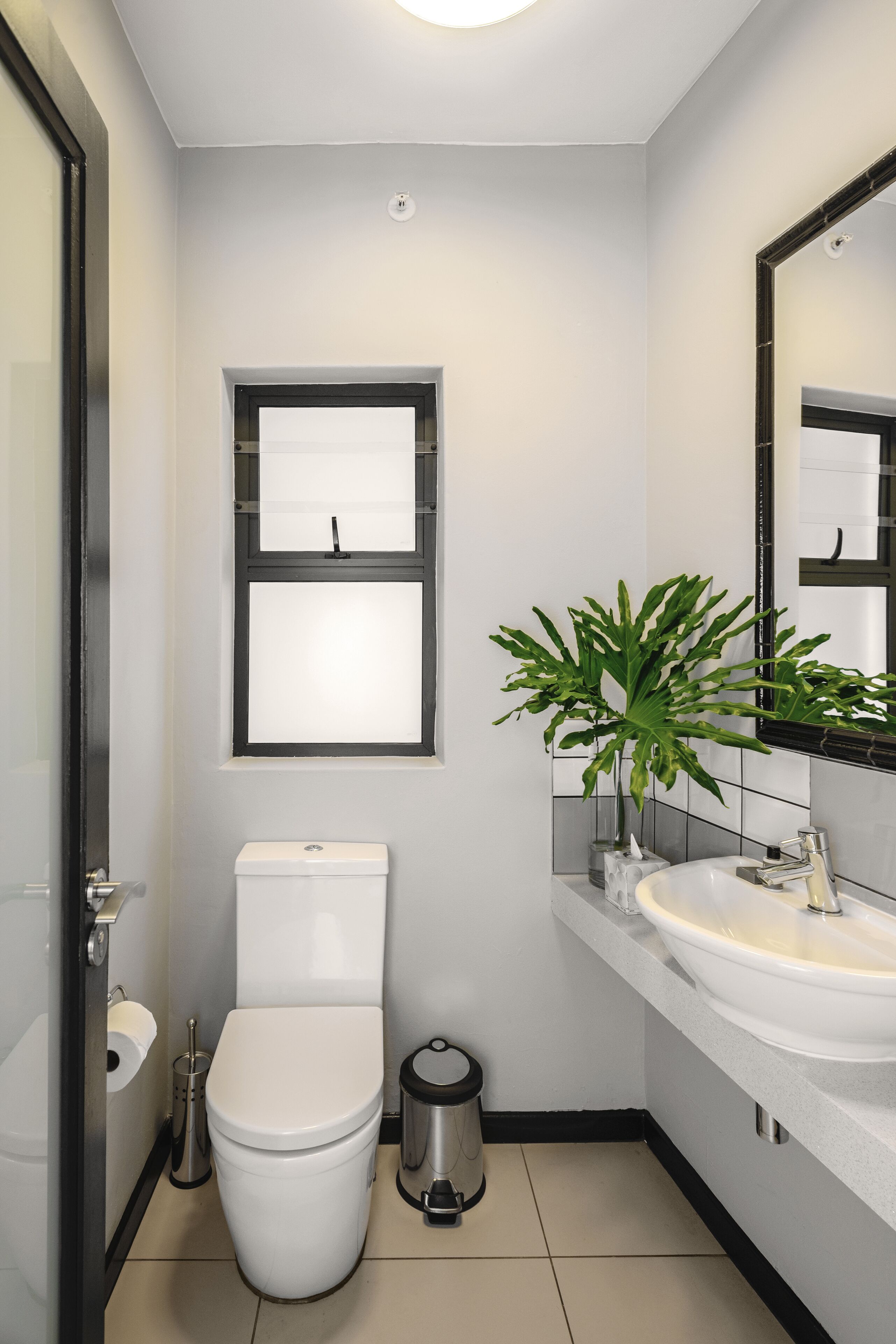 Une salle de bain moderne avec des toilettes, un lavabo et une plante en pot.