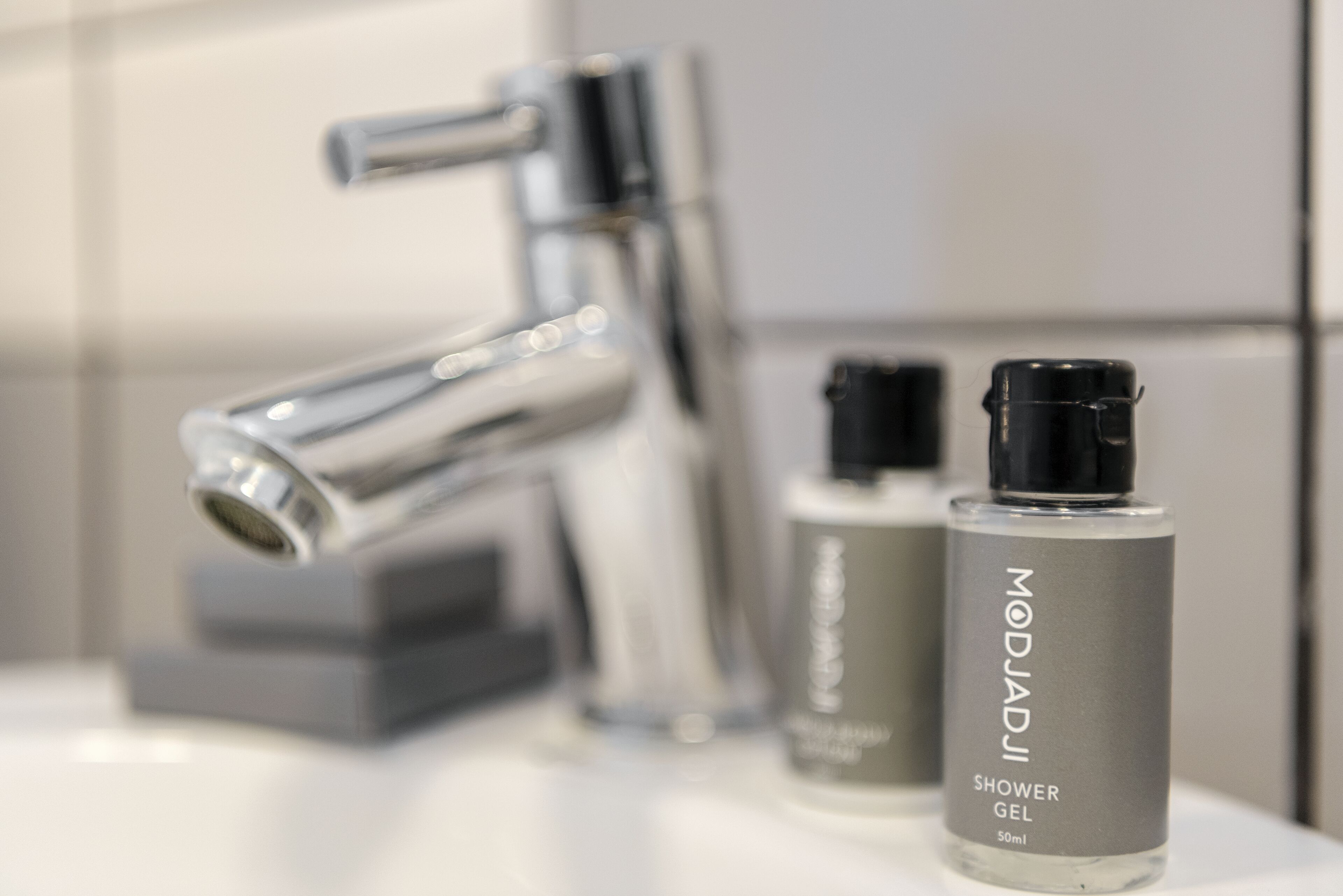 A bathroom with a modern faucet and two bottles of shower gel.