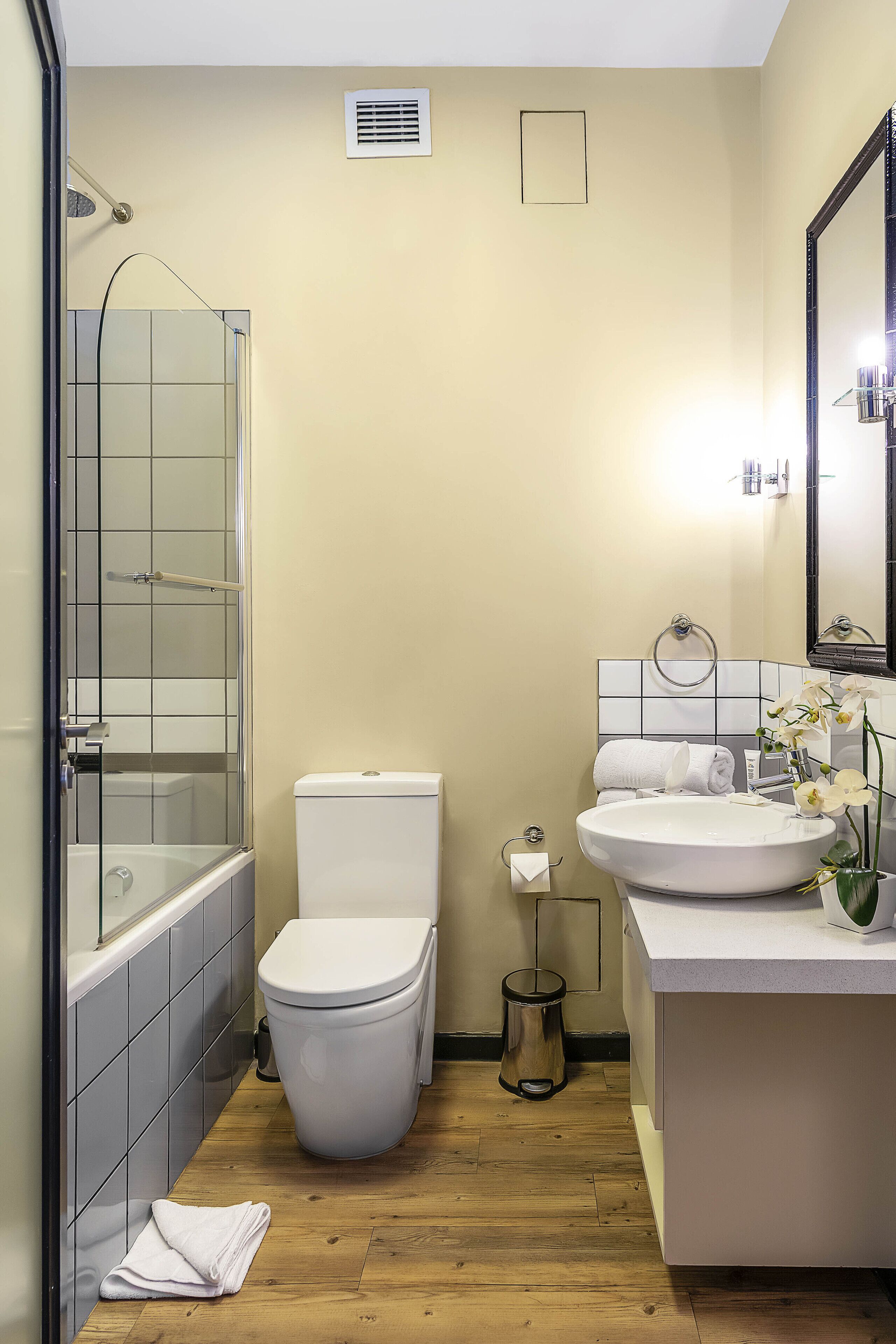 A bathroom with a shower, toilet, sink, and mirror.