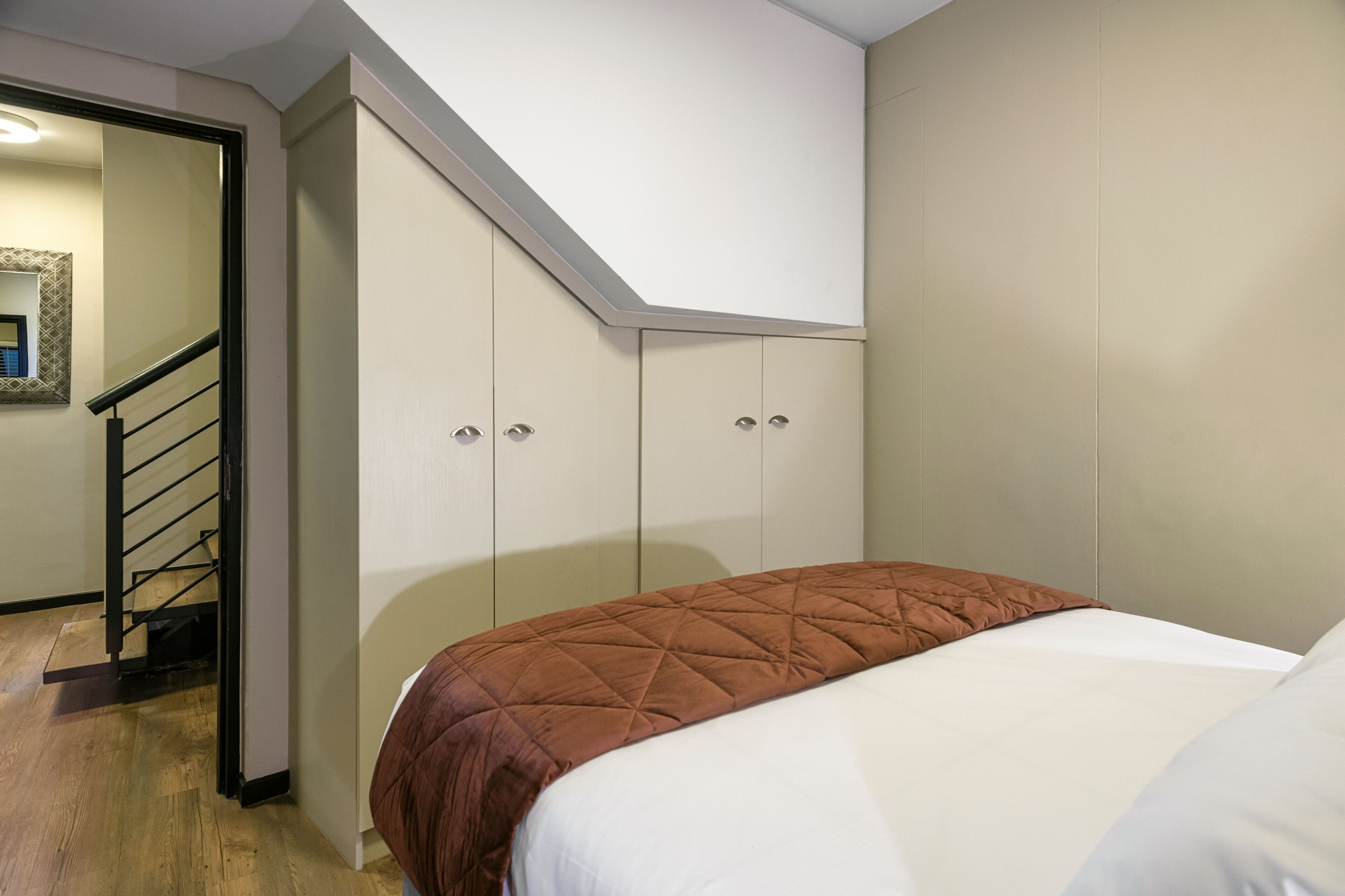 A bedroom with a bed, a wardrobe, and a staircase.