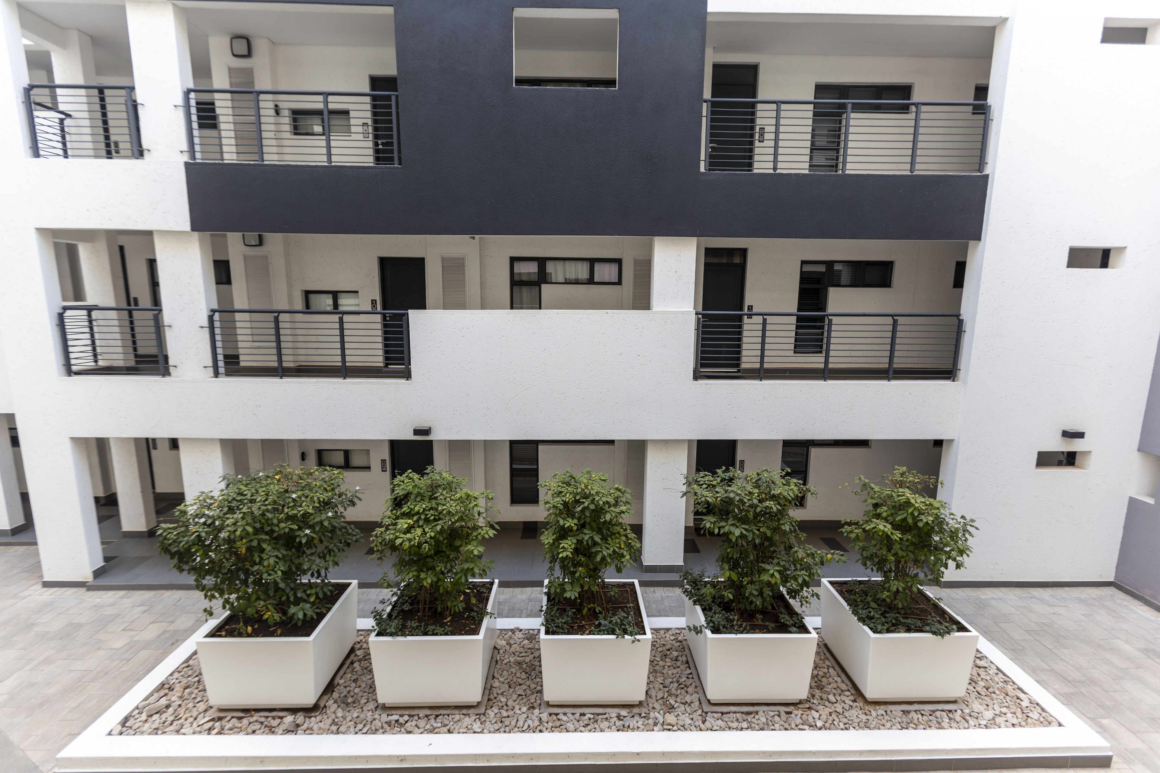 Un edificio a più piani con balconi e una fila di vasi con piante in primo piano.