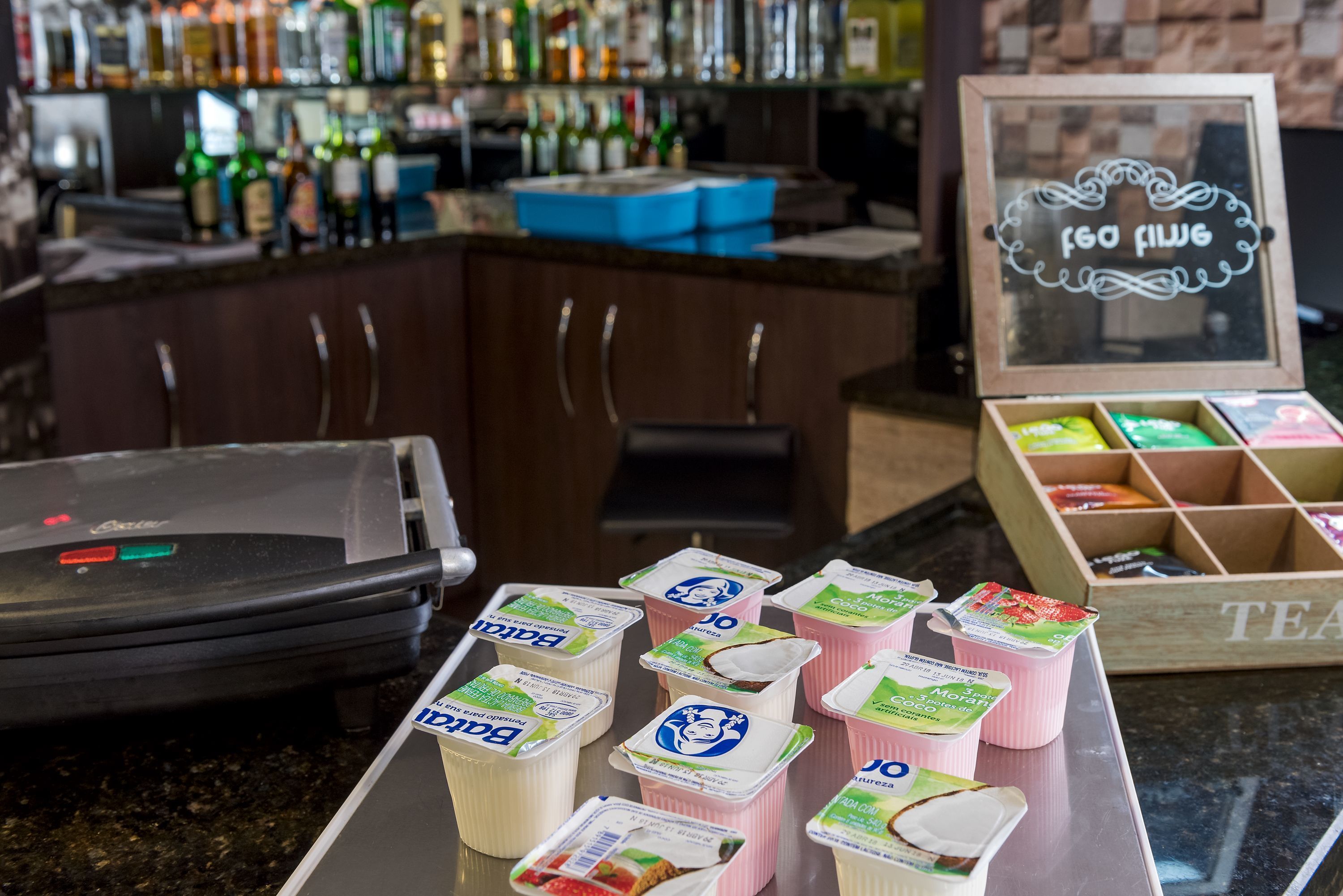 A bar area with a counter displaying various packaged drinks and a cash register.