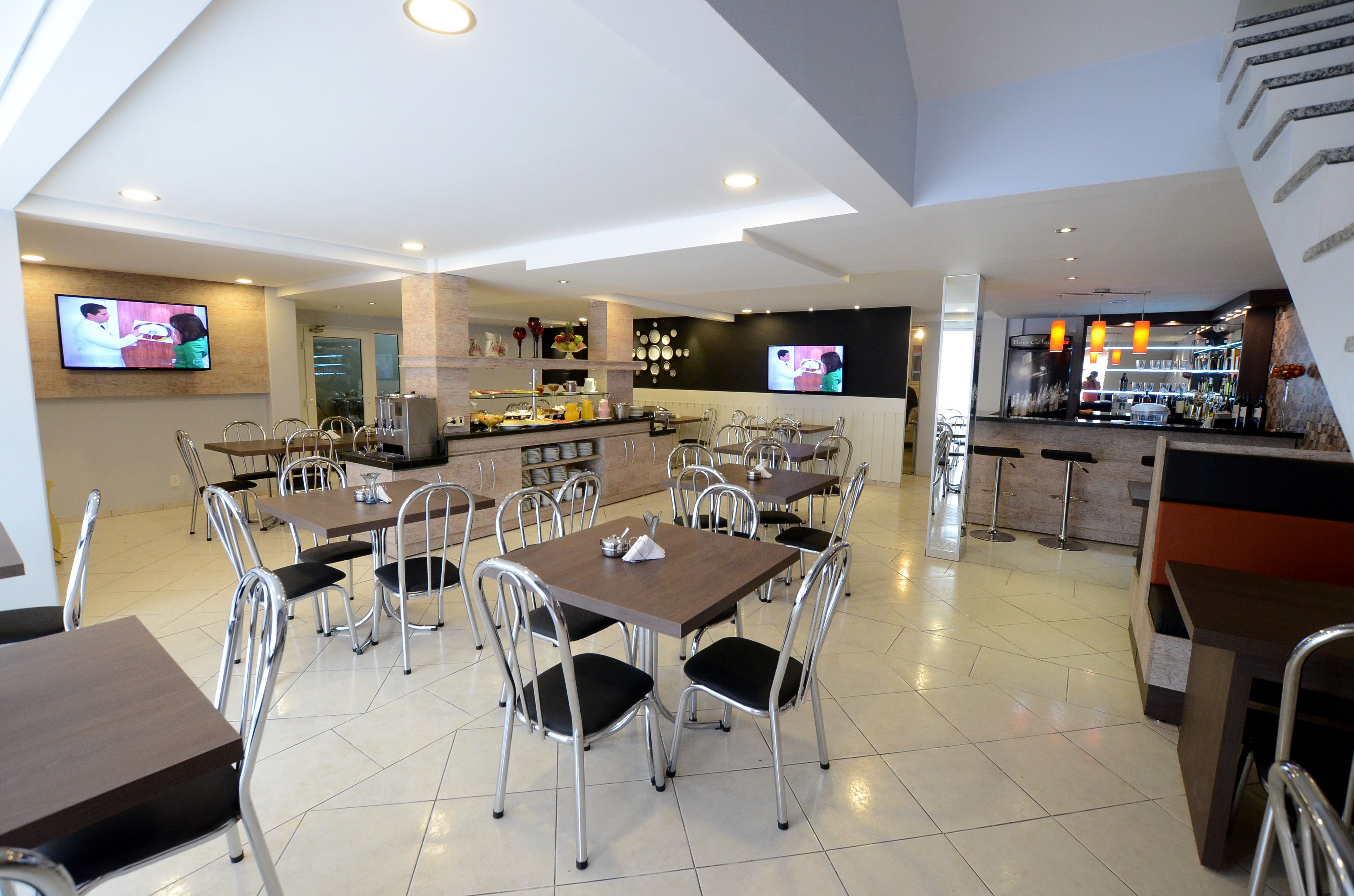 Un restaurante moderno con varias mesas y sillas, una zona de bar y una cocina al fondo.