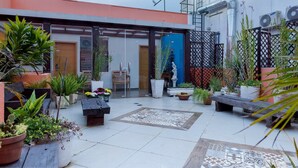 A courtyard with potted plants, a wooden bench, and a tiled floor. - Dom Sollievo Hotel (Telemaco Borba)
