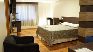 A hotel room with a bed, a desk, a chair, a TV, and a window with curtains. - Dom Sollievo Hotel (Telemaco Borba)