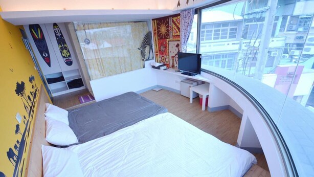 Une chambre d’hôtel moderne dotée d’un grand lit, d’un bureau avec un ordinateur et offrant une vue sur la ville grâce à de grandes fenêtres.