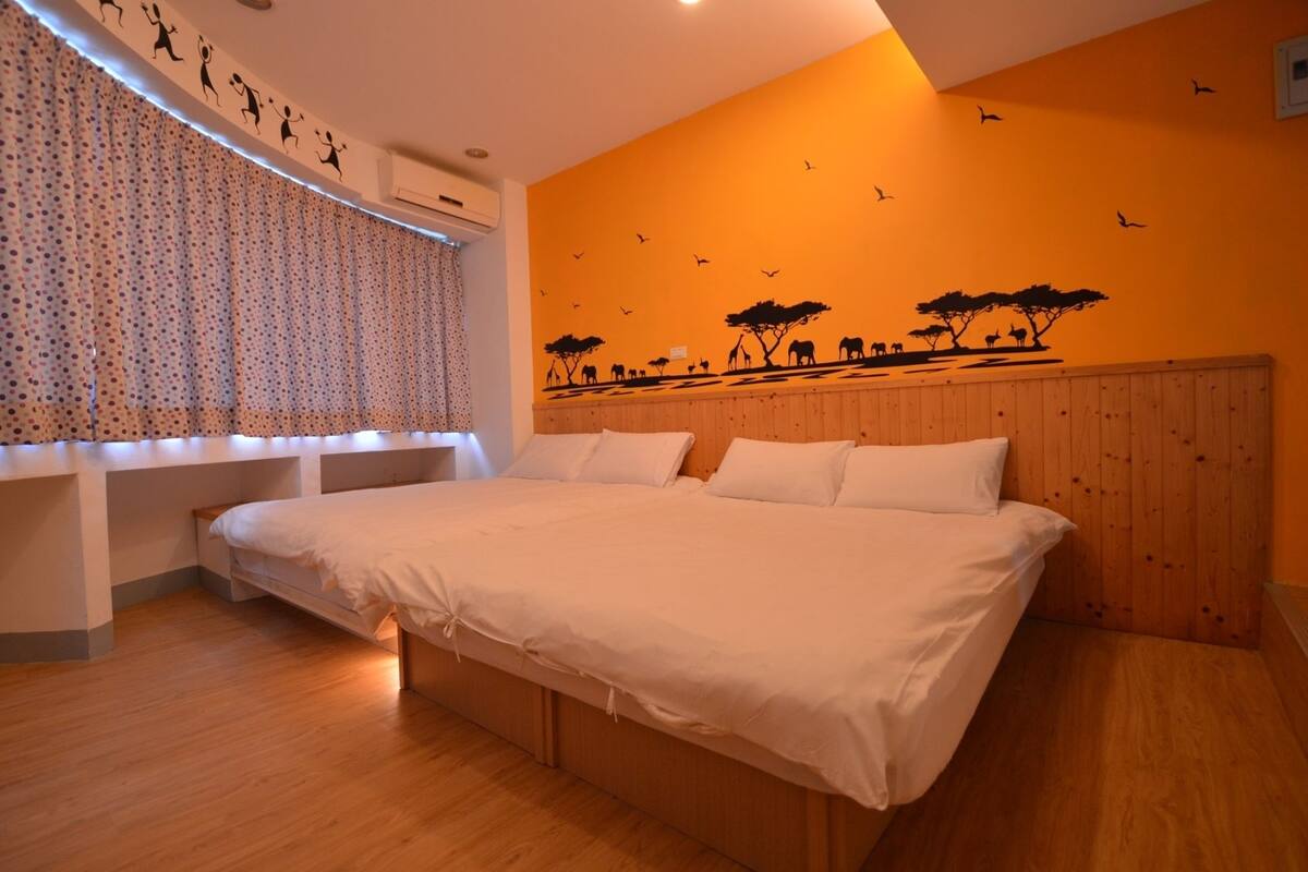 A bedroom with a large bed, wooden headboard, and a wall mural of animals.