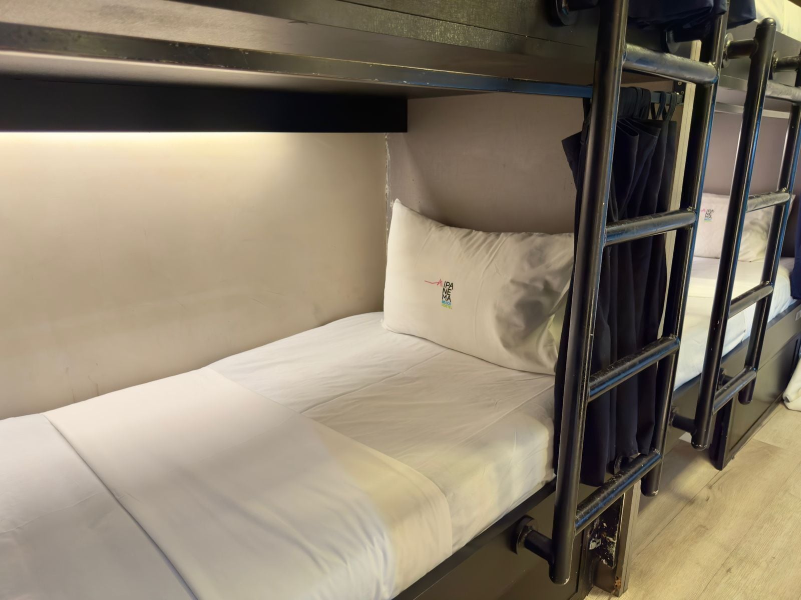 A bunk bed with a white mattress and a pillow with a logo.