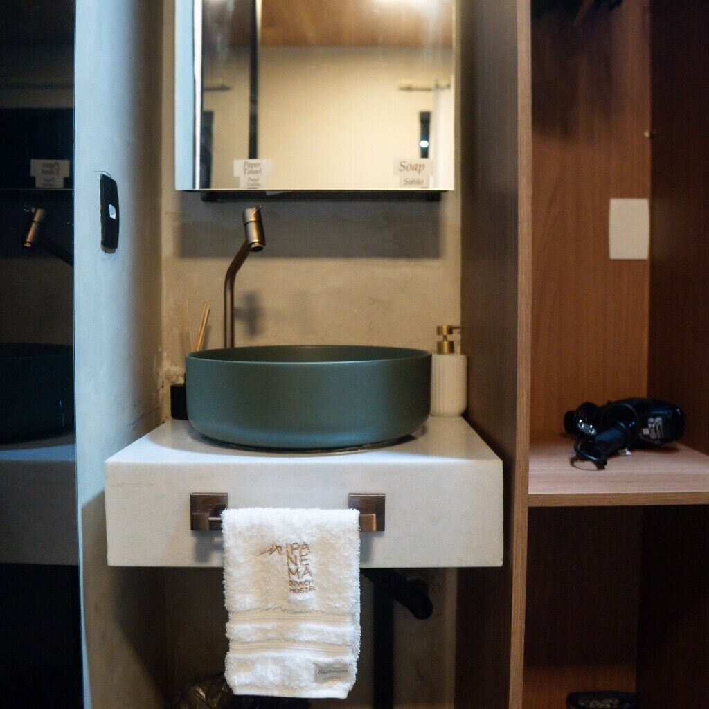 Une salle de bain avec un lavabo rond, un miroir au-dessus et une serviette suspendue à un porte-serviettes.