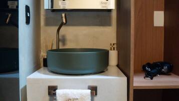 Une salle de bain avec un lavabo rond, un miroir au-dessus et une serviette suspendue à un porte-serviettes.