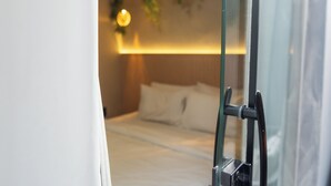 A hotel room with a bed, a bedside table, and a window with a curtain. - Ipanema Beach Hostel (Rio de Janeiro)