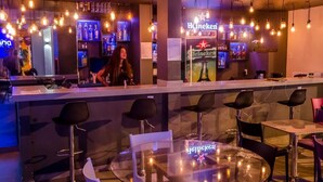 A bar area with a bartender, bar counter, and seating with bar stools. - Ipanema Beach Hostel (Rio de Janeiro)