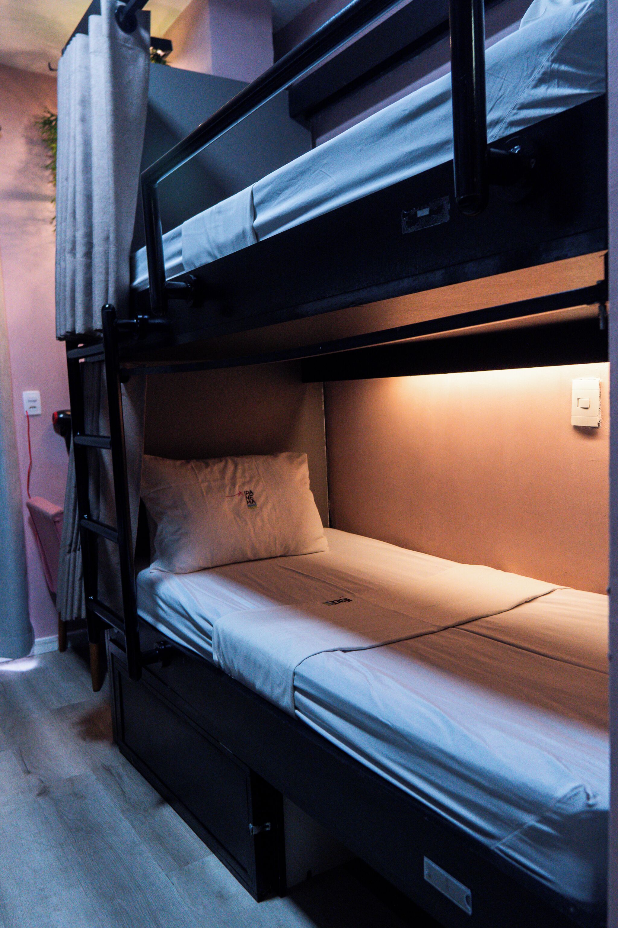 Una cama litera con escalera, un cajón pequeño y un enchufe en la pared.