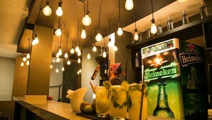 A bar area with hanging light bulbs, a Heineken refrigerator, and a counter with drinks and garnishes. - Ipanema Beach Hostel (Rio de Janeiro)