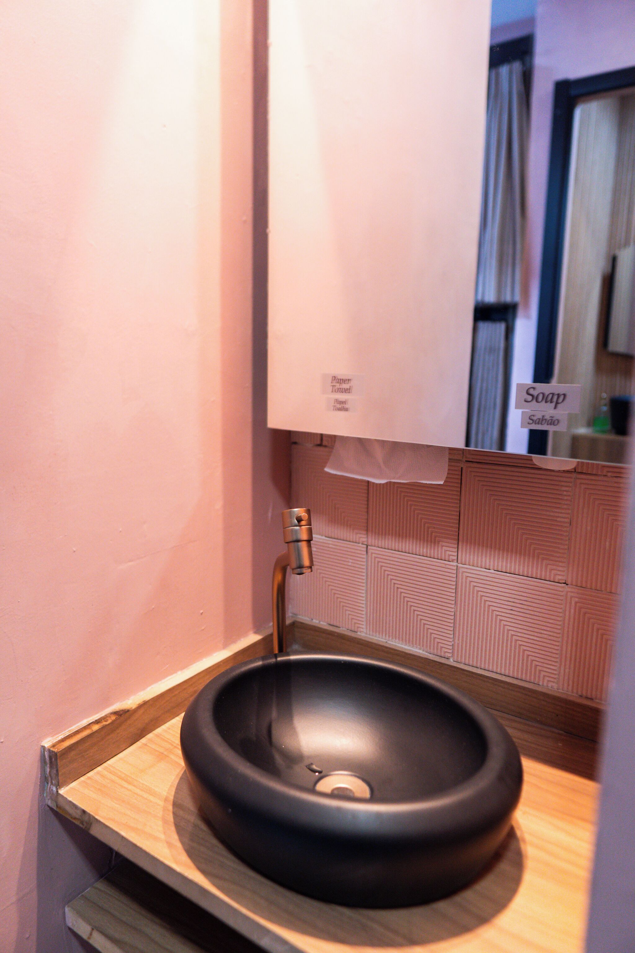 A bathroom with a black sink, a mirror, and a towel hanging on the wall.