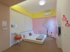 Un dormitorio con cama, aire acondicionado mural, una mesita con una cesta y una decoración de pared con un árbol y un conejo.