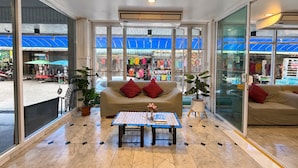 Eine geräumige Lobby mit einem großen Fenster, einem Sofa, einem kleinen Tisch und einer Topfpflanze.