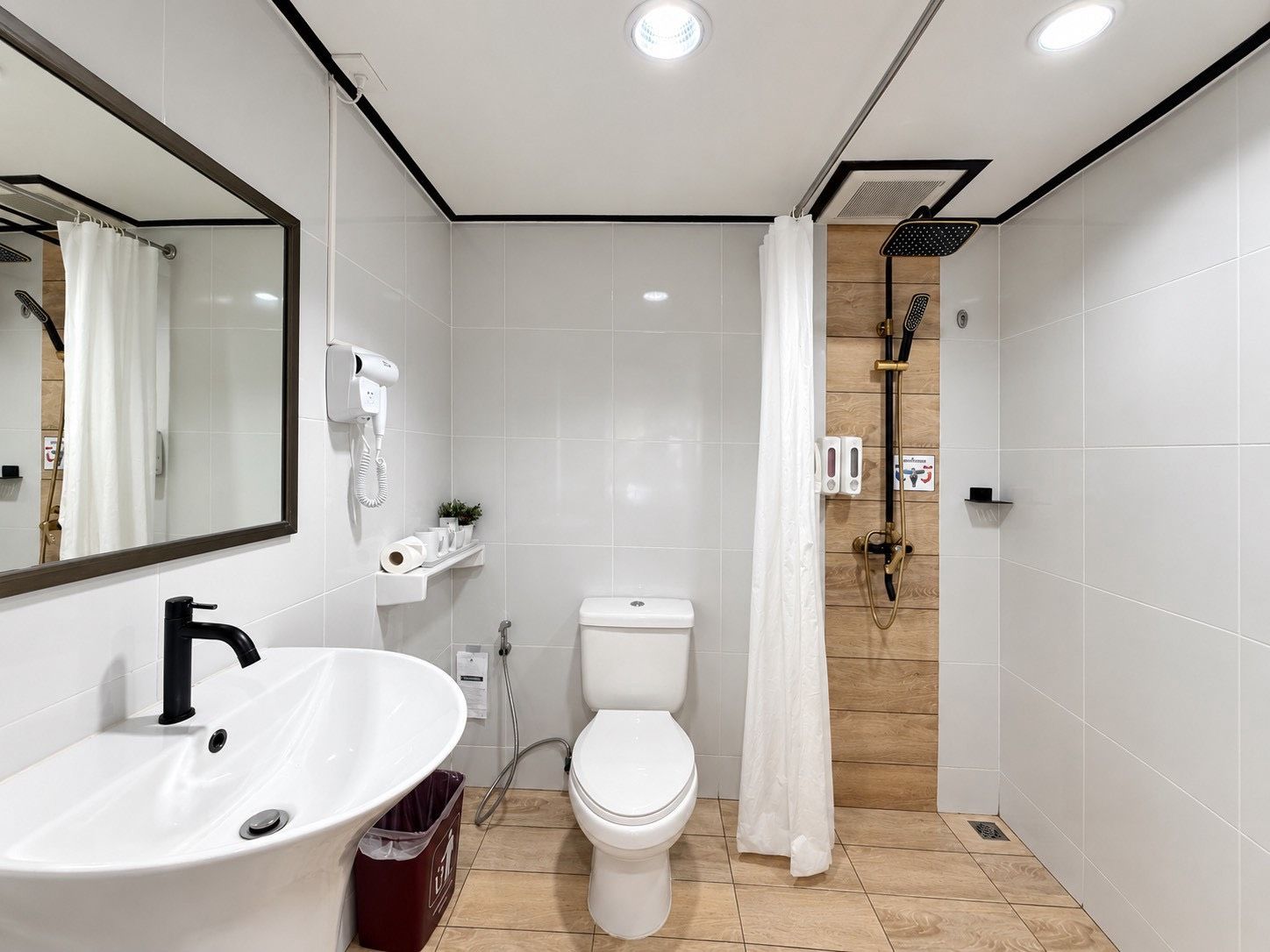 Ein modernes Badezimmer mit Waschbecken, Toilette und Duschbereich, alles in Weiß.