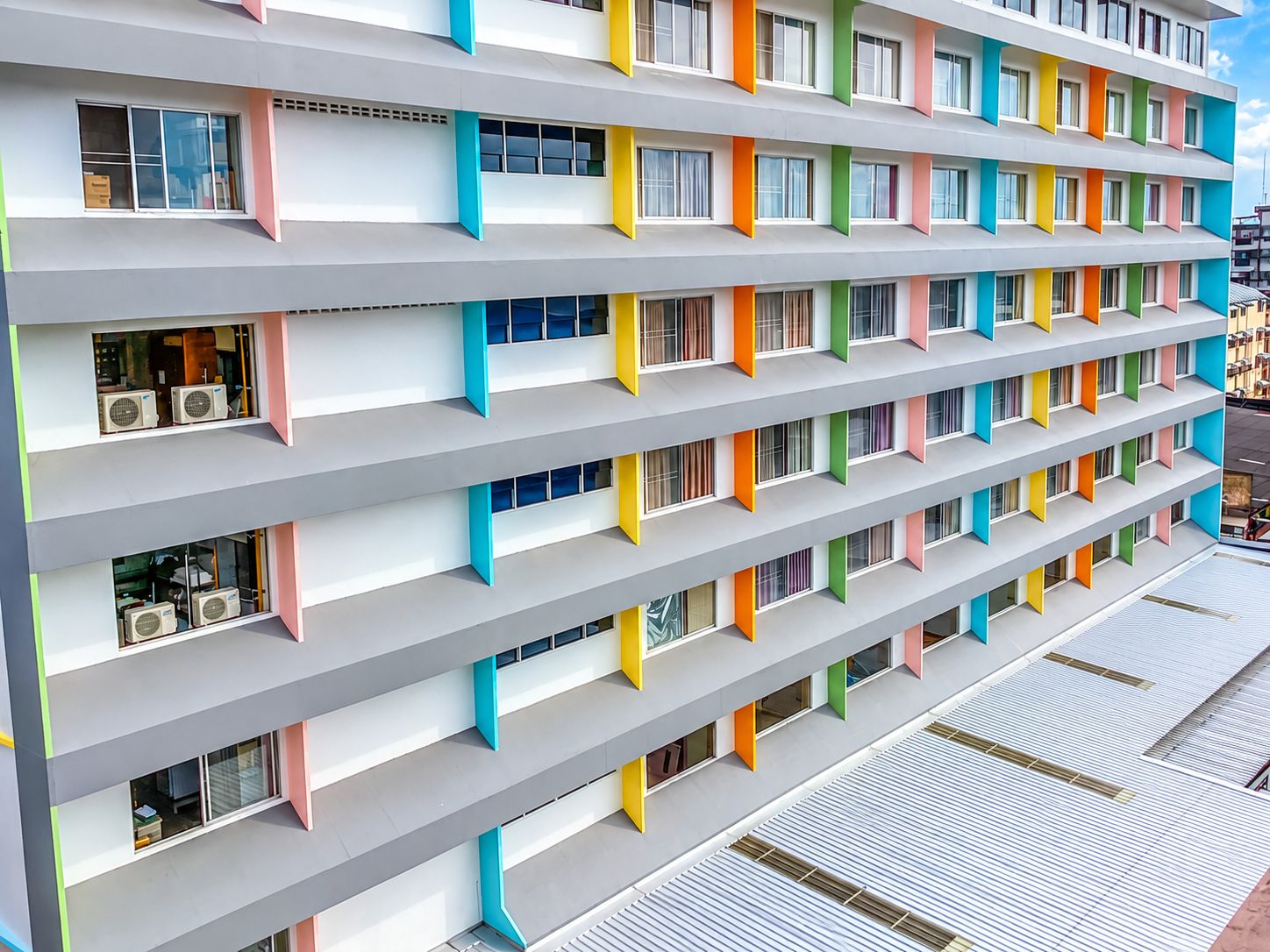 Un hotel de varios pisos con balcones, unidades de aire acondicionado y un diseño arquitectónico moderno.