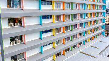 Un hotel de varios pisos con balcones, unidades de aire acondicionado y un diseño arquitectónico moderno.