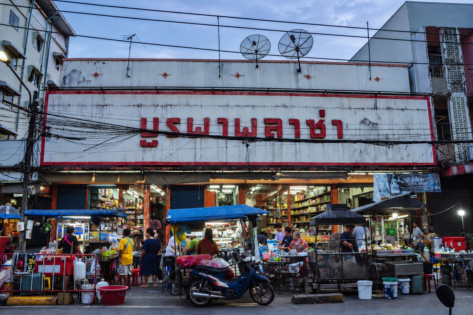 A street market with a prominent building with a sign in a foreign script.