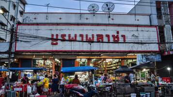 A street market with a prominent building with a sign in a foreign script.