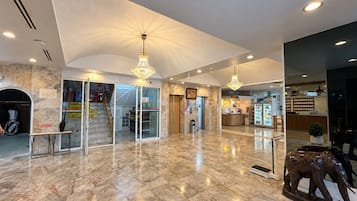 A spacious lobby with marble flooring, a reception desk, a coffee station, and a statue of an elephant.